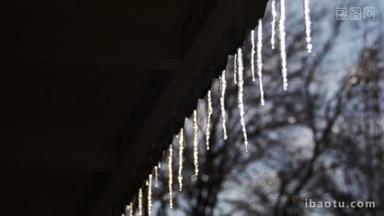 冬天冰柱融化在屋顶下春天的太阳和滴水从他们的提示